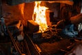 blacksmith holds billet over hot coals in clay oven. blacksmith heating iron metal sword manufacturing marching forge,