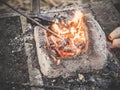 The blacksmith holds the billet over hot coals in a clay oven. blacksmith heating iron metal sword manufacturing