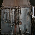 Blacksmith and locksmith tools are hung on the metal wall of the forge furnace Royalty Free Stock Photo