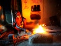 Blacksmith making an object by the fire and a hand hammer in a village of India.