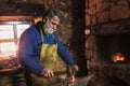 Blacksmith manually forging the molten metal on the anvil in smithy