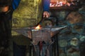 Blacksmith manually forging the molten metal on the anvil in smithy