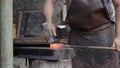 Blacksmith manually forging the molten metal. Close up of the hammer striking