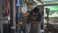 Blacksmith nipping a hot metal rod by machine