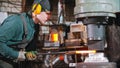 Blacksmith - putting a longer piece of metal under the pressure of industrial forging machine Royalty Free Stock Photo