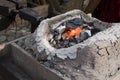 Blacksmith sets up the brazier with embers with large coal tongs. Embers glow in a iron forge. Fire, heat, coal and ash Royalty Free Stock Photo