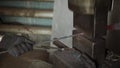 Blacksmith holding candent iron ingot and forging it using pneumatic hammer.