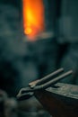 Blacksmith tongs lie on an anvil, in the background a fire in a forge. Royalty Free Stock Photo