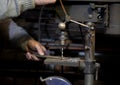 Blacksmith uses drill press in garage. A close up view of a metalworker operating a bench drill inside his workshop.