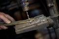 Blacksmith uses drill press in garage. A close up view of a metalworker operating a bench drill inside his workshop.