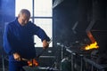 Blacksmith using hammer and pliers for processing hot metal Royalty Free Stock Photo
