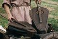 Blacksmith using pair of bellows to kindle fire in furnace