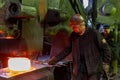 blacksmith worker forging large piece of hot steel in old factory