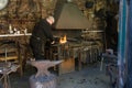 Blacksmith working at his forge with metal in white flame