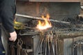 Blacksmith working at his forge with metal in white flame