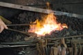 Blacksmith working at his forge with metal in white flame