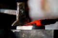 Blacksmith working with red hot metal of new axe on the anvil at the forge Macro photo Royalty Free Stock Photo