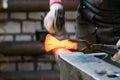 Blacksmith working with red hot metal workpiece of new axe on the anvil at the forge. Focus on red hot metal Royalty Free Stock Photo