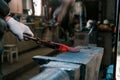 Blacksmith working with red hot metal workpiece of new axe on the anvil at the forge. Focus on hands Royalty Free Stock Photo