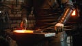 Blacksmith working in the workshop - man hitting the hot red metal with a hammer
