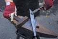Blacksmiths hands holding forceps and a hammer forging a metal billet, blade of a knife, on an anvil