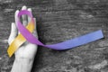 Bladder cancer awareness marigold blue purple ribbon on helping hand suport isolated with clipping path