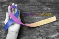 Bladder cancer awareness marigold blue purple ribbon on helping hand support isolated with clipping path