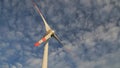 The blades of the wind station are spinning against the beautiful blue sky.