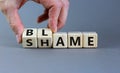 Blame or shame symbol. Businessman turns wooden cubes and changes the word `shame` to `blame` or vice versa. Beautiful grey