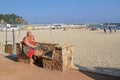 Senior woman sitting on stone bench and taking sunbath on beach of Blanes