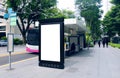 Blank advertising poster banner mockup at bus stop shelter by main road; out-of-home OOH vertical billboard media display space. Royalty Free Stock Photo