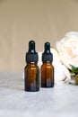 Blank amber glass dropper bottle with serum or essential oil and white peony flowers. Natural organic cosmetic concept