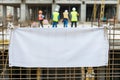 blank banner tied to a metal grid with site workers in the back Royalty Free Stock Photo