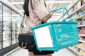 Blank billboard attached to a supermarket basket. Girl holding shopping basket in another. Woman doing food shopping Royalty Free Stock Photo