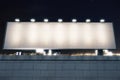 Blank billboard with lights on the top of brick wall at night ci Royalty Free Stock Photo