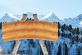 Blank billboard for outdoor advertising from logs and a wooden board on a ski slope against a background of snow-capped Royalty Free Stock Photo