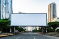 Blank billboard ready for new advertisement in city with skyscrapers, located above the roadway