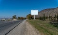 Blank billboard sign by empty highway through mountains landscape. Royalty Free Stock Photo