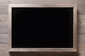 Blank black board in a wooden frame against a wooden surface Royalty Free Stock Photo