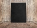 Blank black canvas poster leaning at wood wall on wooden floor i Royalty Free Stock Photo