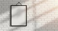 A blank black framed picture hanging on a white brick wall with dappled sunlight and shadows Royalty Free Stock Photo