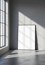 Blank black framed poster leaning against a grey wall with window light shadows white Royalty Free Stock Photo
