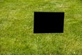 Blank black information sign on spikes standing on a green grass lawn Royalty Free Stock Photo