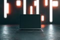 Blank black laptop screen on dark concrete surface with abstract blurry nights lights background. Mockup
