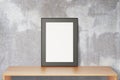 Blank black picture frame on wooden table and concrete wall, mock up Royalty Free Stock Photo