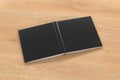 Blank black square open and upside down book cover on wooden background isolated with clipping path around cover. Royalty Free Stock Photo