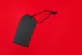 Blank black tag on red background with copy space. Price tag, gift tag, sale tag, address label, etc