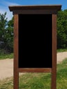 Blank black vertical rectangular pylon stand on forest dirt road mock up. Empty panel for advertisement, promotion