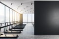 Blank black wall in modern loft style gym with black treadmills at sunset