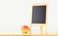 Blank blackboard with red apple on wood table at grey background Royalty Free Stock Photo
